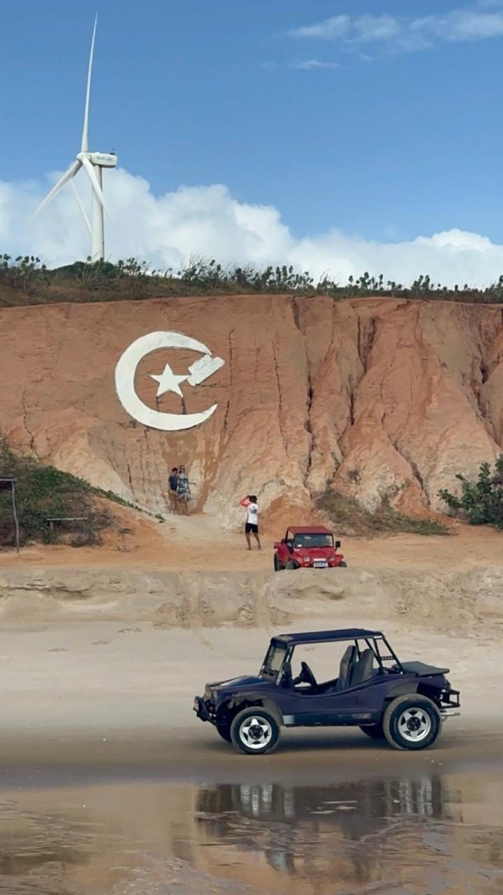 Buggy na praia de Canoa Quebrada em frente às falésias com o símbolo da lua e estrela
